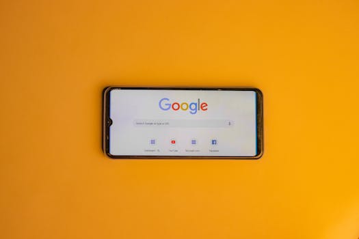 Smartphone displaying Google search page on a vibrant yellow background.