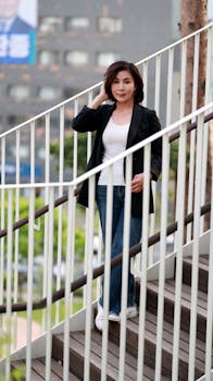 Woman in casual wear standing on a staircase in a Seoul city street, showing confidence and style.