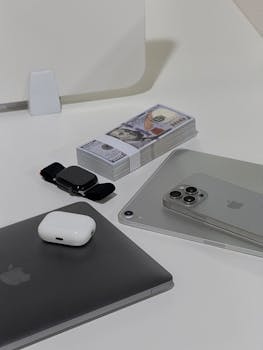 A sleek arrangement of high-tech gadgets and dollar bills on a minimalist desk.